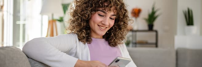 Una chica sentada en un sofá con el móvil